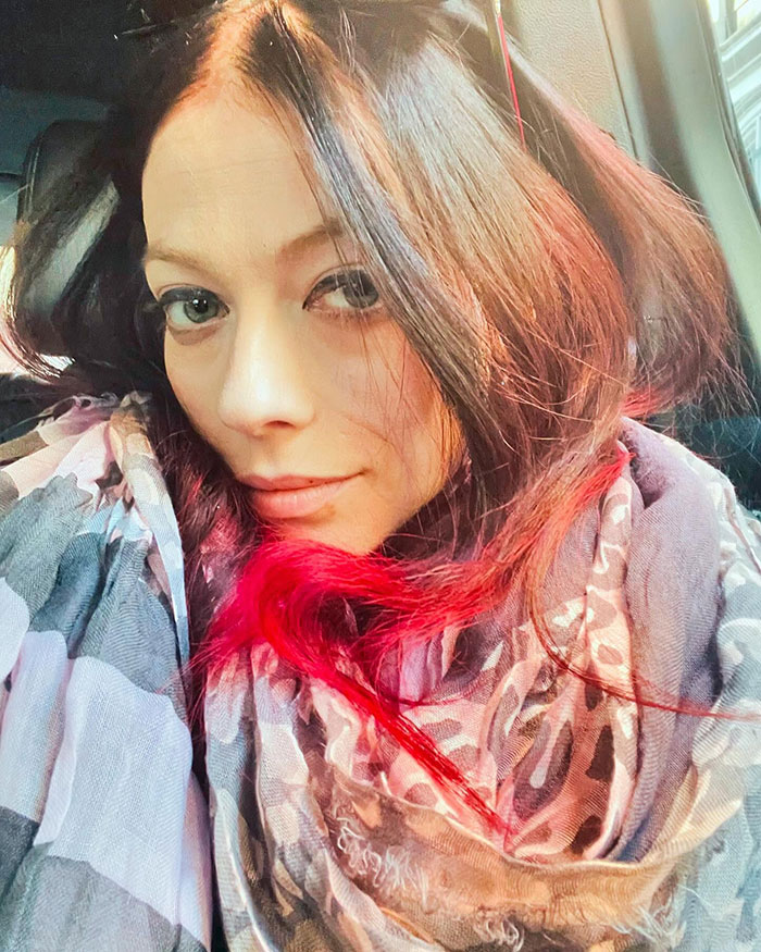 No estoy seguro de quién es este. La persona tiene el pelo largo y castaño con reflejos rojos, con una bufanda estampada en un retrato de primer plano.