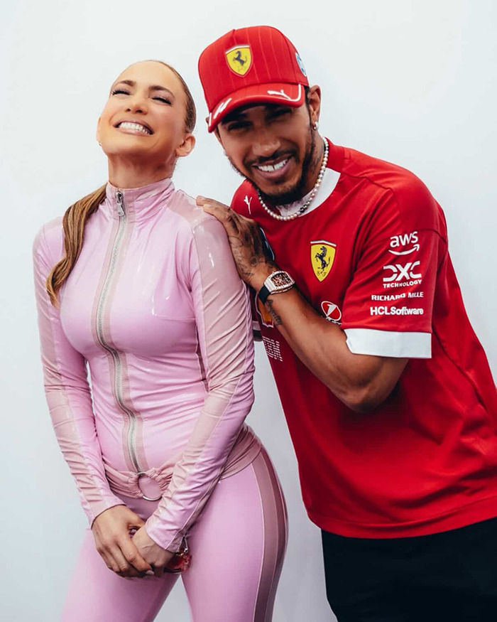 Mujer en Catsuit rosa con atleta, ambos sonriendo en la carrera saudita de F1.