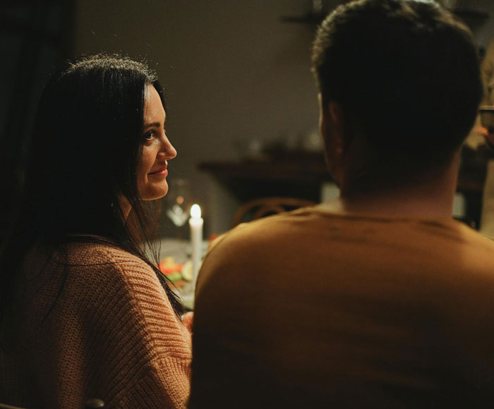 Mujer y hombre en una cena de compromiso a la luz de las velas, creando un ambiente íntimo.