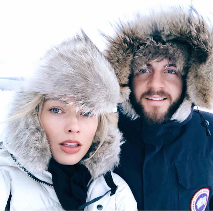 Dos personas en abrigos de invierno con capuchas de piel en un entorno nevado, mostrando un aspecto natural posparto.