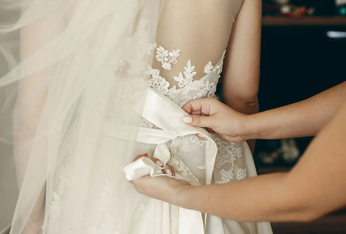 Novia con bata de encaje, manos ajustando el arco, que representan las tensiones de boda.