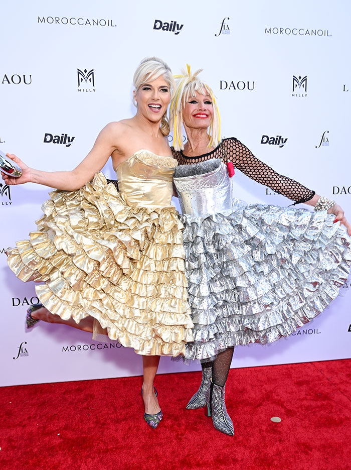 Dos mujeres con vestidos con volantes en la alfombra roja, expresando una personalidad increíble en un evento de moda.