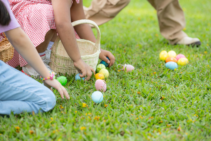 Niños recolectando huevos de Pascua en hierba, con cestas coloridas.