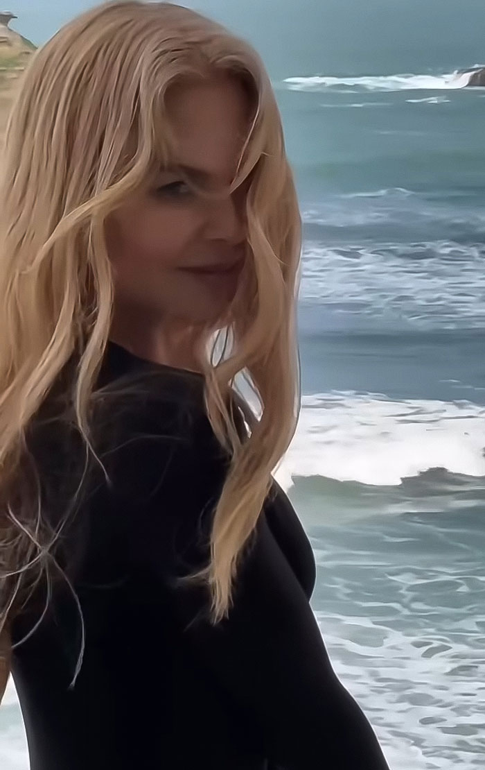 Nicole Kidman junto al océano, con negro, con el pelo largo y rubio soplando en el viento durante un momento al aire libre.