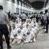 En esta foto proporcionada por la oficina de prensa presidencial de El Salvador, un guardia de la prisión transfiere a los deportados de los EE. UU., Sumule que son miembros de pandillas venezolanas, al Centro de Confinamiento del Terrorismo en Tecoluca, El Salvador, el domingo.
