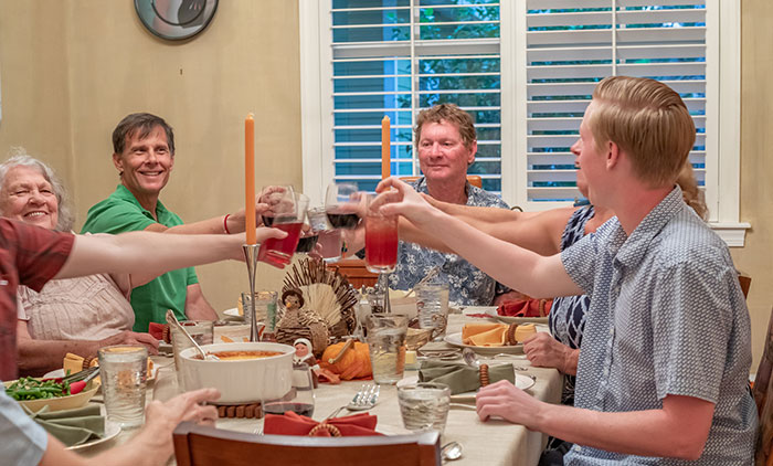 La familia se reunió alrededor de la mesa del comedor, criando vasos durante una celebración tradicional, destacando los temas familiares y tradicionales.