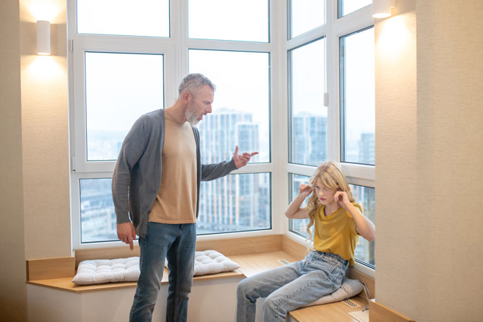 Papá e hijo en un momento tenso cerca de una ventana durante una discusión de la cena de compromiso.