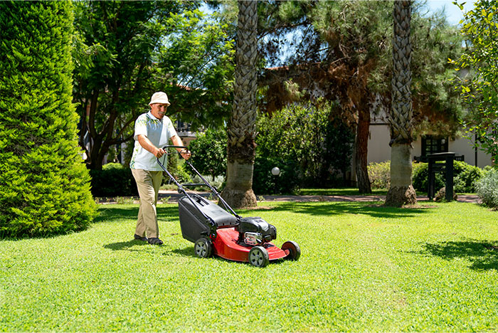 Hombre cortando el césped en un exuberante patio que se ha transformado en un hábitat certificado de vida silvestre con vegetación natural.
