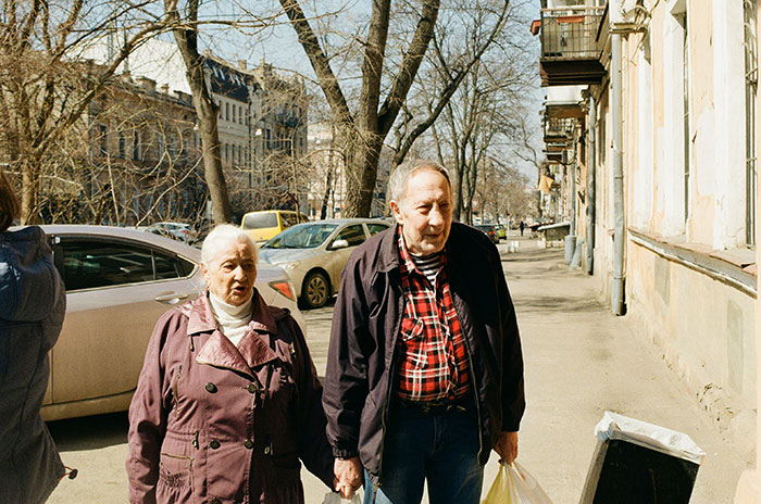 Pareja de ancianos caminando por una acera de la ciudad, ilustrando las preocupaciones de seguimiento del teléfono con la ubicación de monitoreo de los padres.
