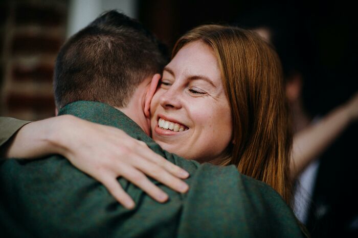 Mujer sonriendo calurosamente mientras abraza a un hombre, ilustrando la amabilidad y la armonía como un secreto para la longevidad y el envejecimiento.
