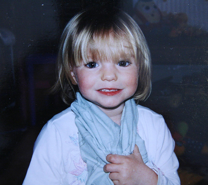 Young Blonde Girl sonriendo y sosteniendo una tela azul, relacionada con las noticias de solicitud urgente de la policía alemana de Madeleine McCann.