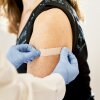 Doctor solicita un vendaje el brazo de un paciente después de una inmunización.