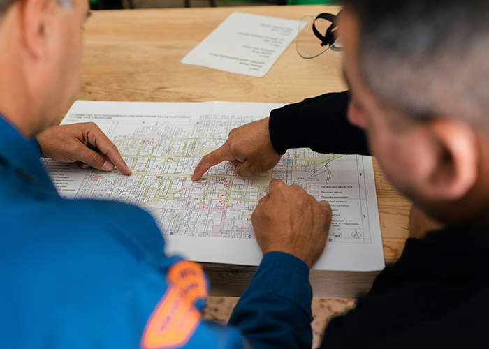 Dos hombres examinan de cerca un mapa detallado, centrándose en la planificación y la resolución de problemas en un contexto de ingeniería.