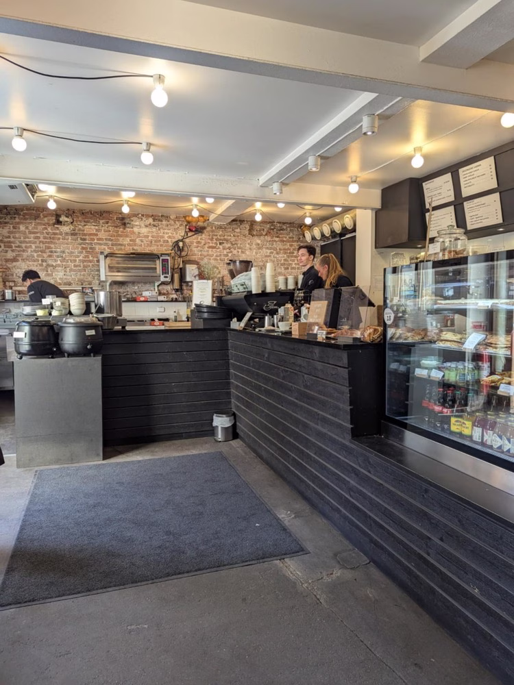 Una mirada dentro de Da Matteo, un café en Gotemburgo, Suecia. La barra de café espresso está cubierta con máquinas de café espresso y molinillos de café, junto con tazas hasta las tazas y una variedad de pasteles. Los baristas están detrás del bar, ocupado trabajando.