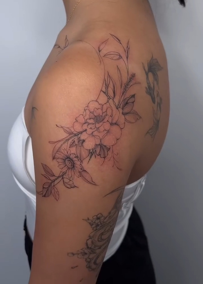 Diseño de tatuajes florales en la parte superior del brazo y el hombro, destacando el tatuaje del tatuaje y las tendencias en 2025.