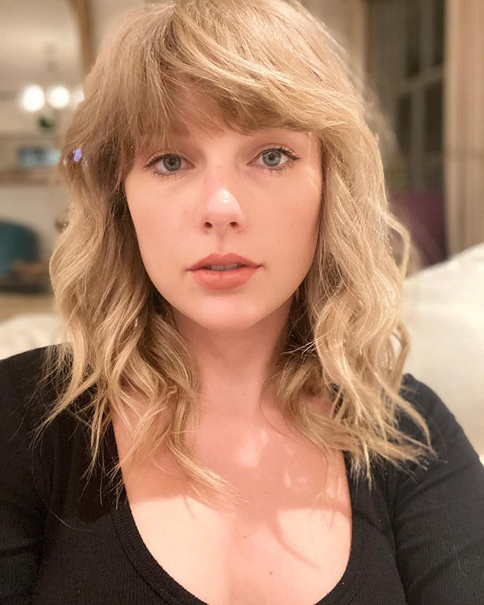 Primer plano de una mujer con cabello rubio y ojos azules, en un entorno interior informal, relacionado con Elon Musk y la controversia que verifica el cuerpo.