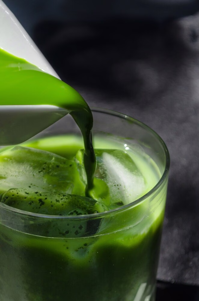 Un primer plano de Matcha se vierte en un vaso sobre hielo.