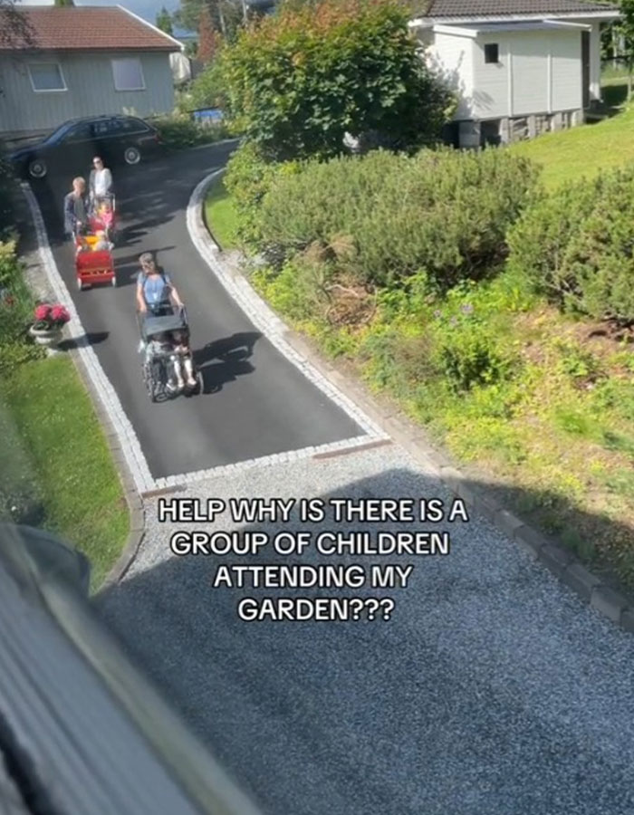 La mujer mira desconcertada mientras extraños se reúnen haciendo un picnic en su patio en un día soleado cerca de un sendero de jardín.