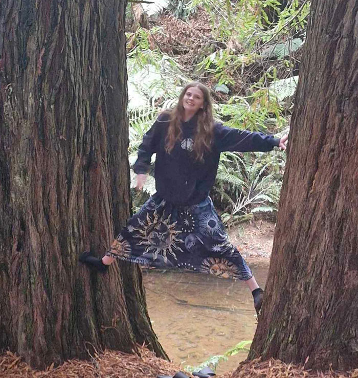 Adolescente equilibrada entre dos árboles grandes en el bosque, relacionado con el texto final de la adolescente desaparecida que desapareció en el aeropuerto.