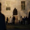 La gente se reúne para tomar fotos con la estatua de John Harvard en la Universidad de Harvard. El presidente Trump hizo otra amenaza para el estado exento de impuestos de Harvard en un puesto de redes sociales el viernes.