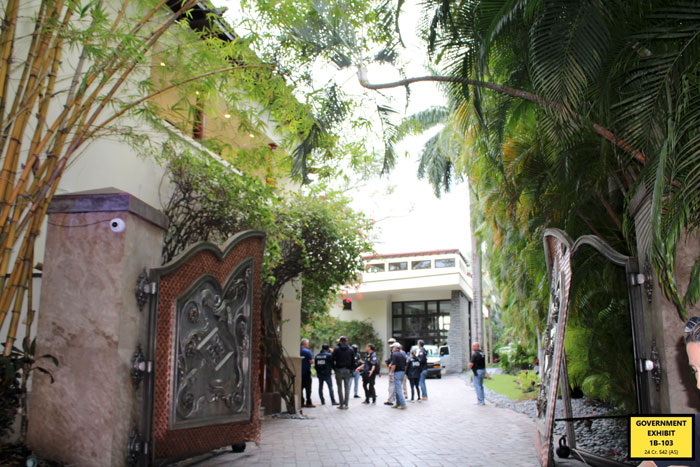 Entrada de la mansión cerrada con la policía y las personas reunidas afuera, relacionadas con el caso judicial que revela los desagradables hábitos alimenticios.