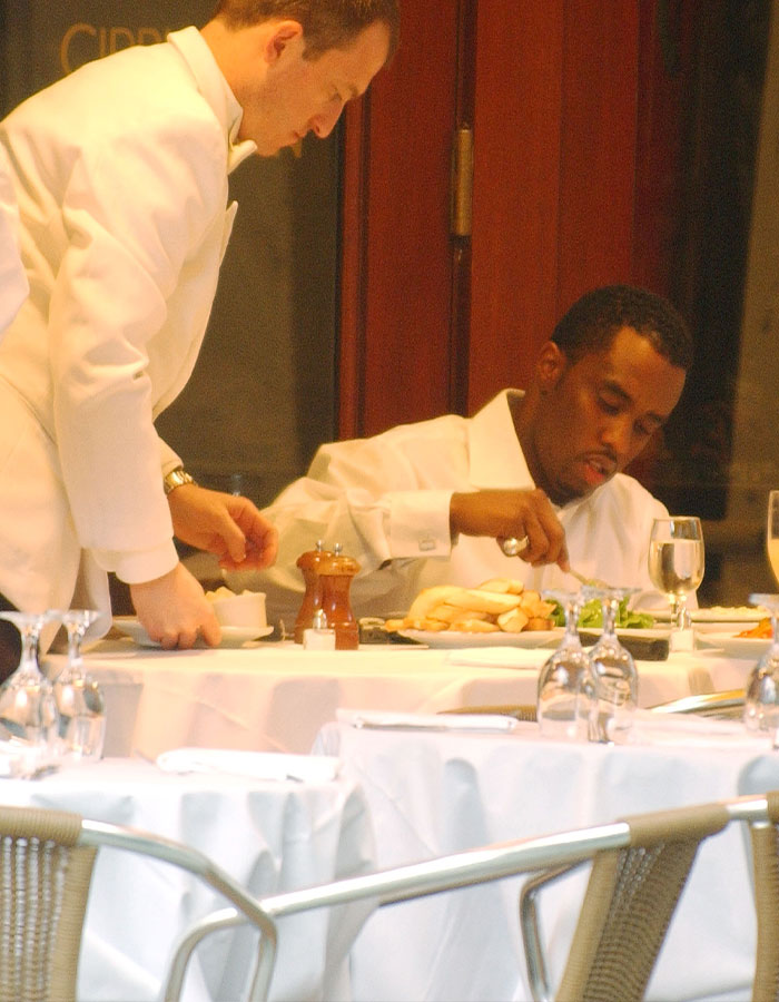 El hombre se parece a Diddy comiendo en una mesa mientras el camarero sirve, destacando el asco y los rebeldes hábitos alimenticios revelados por el personal.
