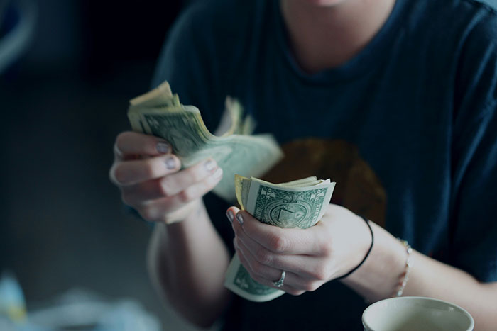 Persona que contaba billetes de dólar, destacando las disputas de pago de niñera después de que el bebé se queda dormido durante la sesión de atención