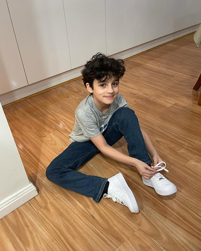 El joven sentado en el piso de madera que ataba zapatillas blancas, relacionadas con la recaudación de fondos para congelar el cuerpo después de 13 años, hijo se le quitó la vida.