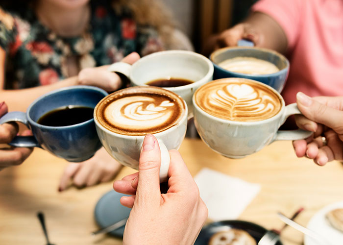 Grupo de personas con tazas de café con arte de café con leche, destacando la interacción Barista e Decaf Venge.