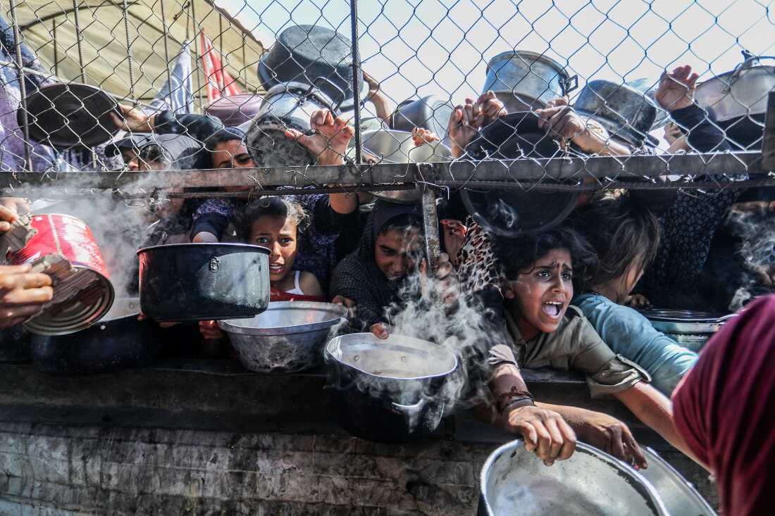 Los palestinos desplazados, incluidas las mujeres y los niños que viven en tiendas de campaña, reciben alimentos distribuidos por organizaciones de ayuda en el distrito de Al Mawasi de Khan Yunis, Gaza, el 30 de mayo de 2025, la situación destaca la creciente desesperación y la necesidad urgente de asistencia humanitaria en el enclave despido.