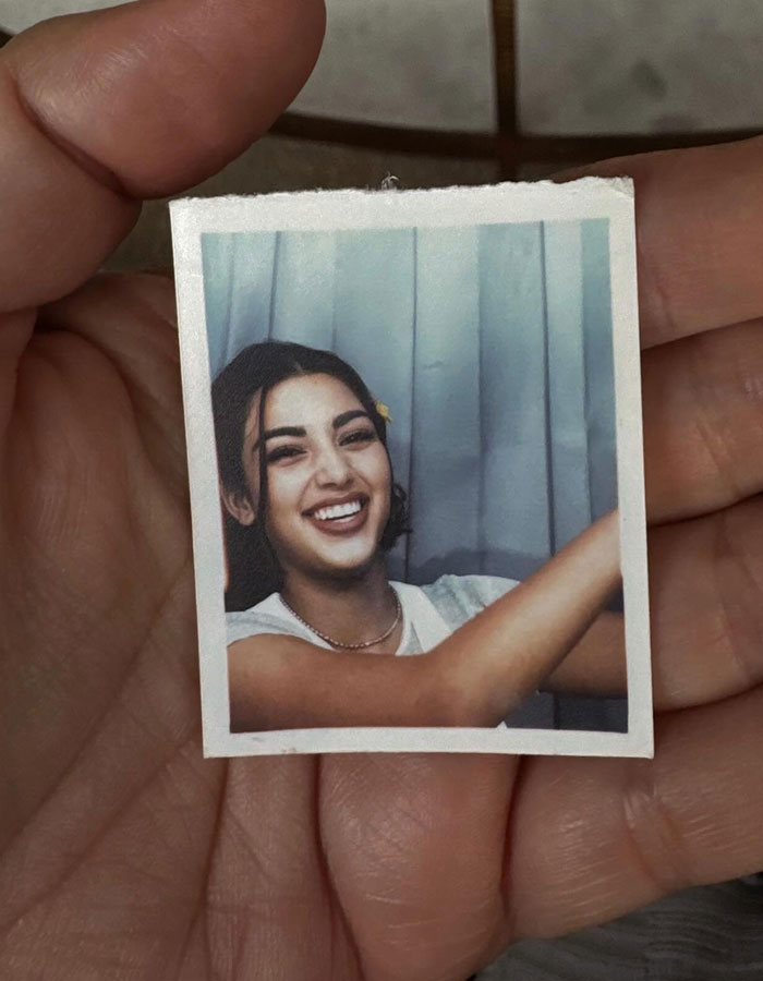 Mano sosteniendo una foto vintage de una mujer sonriente, provocando discusiones sobre las cirugías de plástico de Kim Kardashian.
