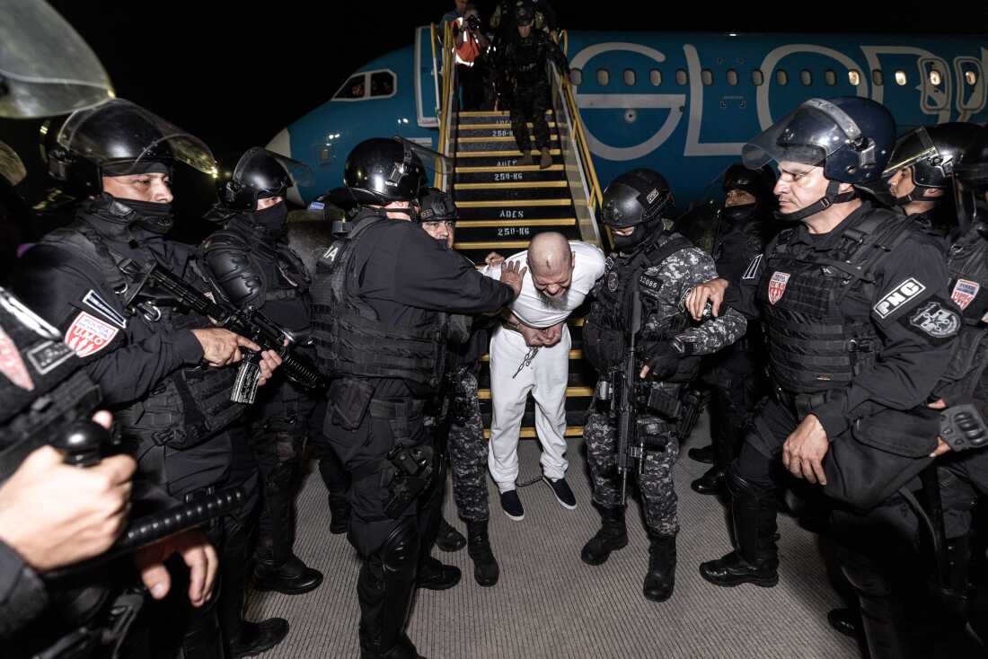 Los guardias escoltan a uno de los cientos de presuntos miembros de las pandillas 'Tren de Aragua' y Mara Salvatrucha que fueron deportadas de los Estados Unidos a El Salvador.