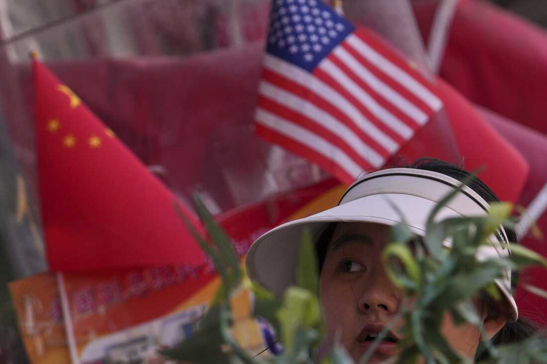 Una mujer pasa por las banderas nacionales chinas y de los Estados Unidos en exhibición en una tienda de mercancías en Beijing.
