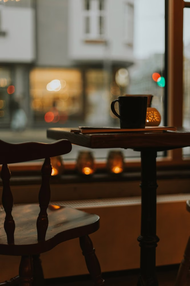 Transparencia en el café: una imagen de un café con poca luz. Una taza de café se sienta en una mesa junto a una silla vacía.