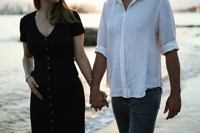 Pareja tomada de la mano caminando por la playa al atardecer, ilustrando conflictos familiares y problemas de hermano de naipes.