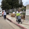 El veterano de la guerra de Iraq, Irving Webb, mueve sus pertenencias a medida que los trabajadores de saneamiento aclaran la acera, donde pasó algunas noches en abril, fuera del campus de Los Ángeles VA.