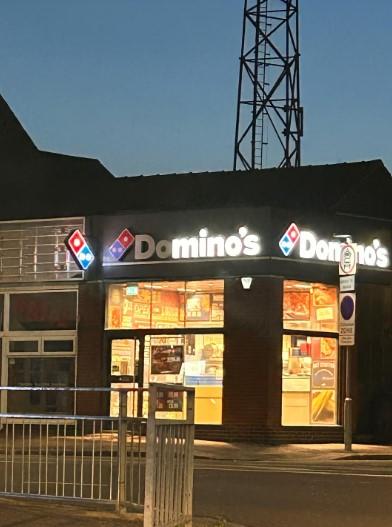 Una imagen de un restaurante Domino's con la mayoría de las luces apagadas, excepto las que leen 