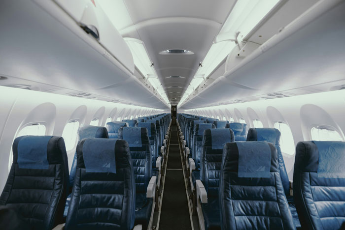 Interior de cabina de avión vacío con hileras de asientos, relacionado con el actor tailandés que sobrevivió a un accidente aéreo y a Air India Survivor Link