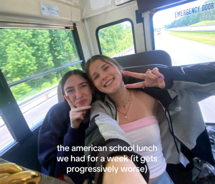 Dos adolescentes sonriendo en un autobús que muestra reacciones a los almuerzos escolares estadounidenses descritos como progresivamente peor durante una semana