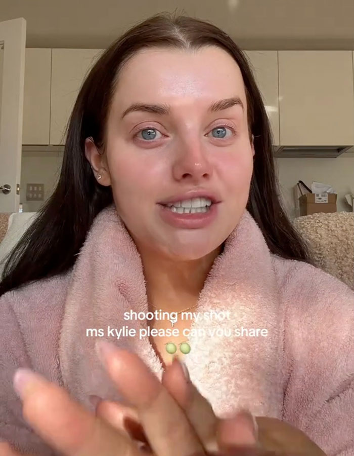 Una mujer con una túnica rosa que habla con la cámara sobre los detalles de la cirugía de aumento de senos de Kylie Jenner.