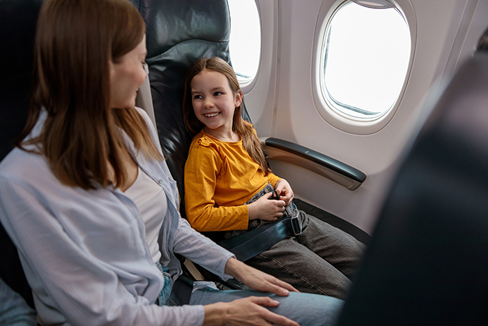 Mujeres y niños sentados en el avión cerca de la ventana, centrándose en la situación de viajes y aeropuertos con problemas de pasaporte.