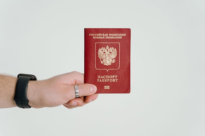 Mano sosteniendo un pasaporte ruso, simbolizando el pasaporte de un ex muerto revocado y varado en el aeropuerto.