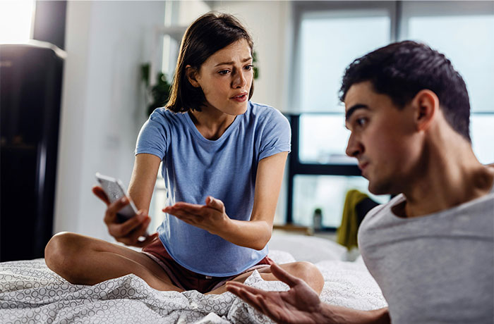 Pareja tiene una conversación tensa en el dormitorio con una mujer explicando, destacando problemas de limpieza desordenados en casa y enfermedades.