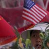 Una mujer pasa por las banderas nacionales chinas y estadounidenses en exhibición en una tienda de mercancías en Beijing.