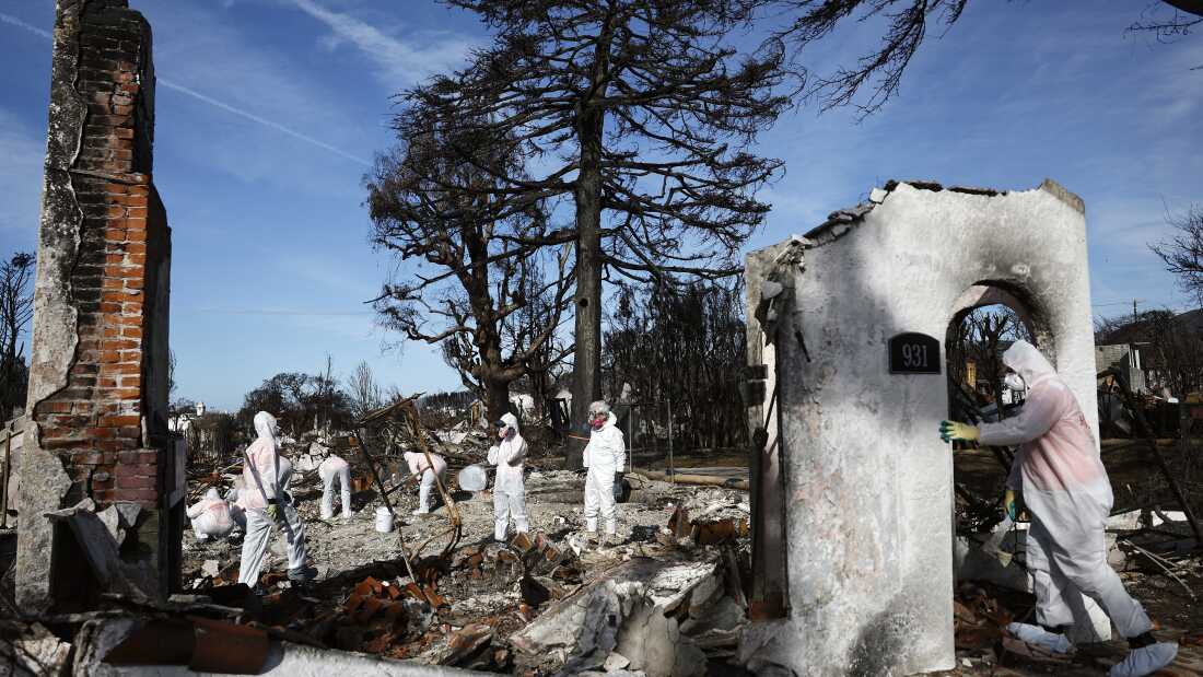 Los voluntarios ayudan a un propietario a buscar artículos personales en los restos de una casa que quemó en el incendio de Palisades en enero de 2025 en Pacific Palisades, California.