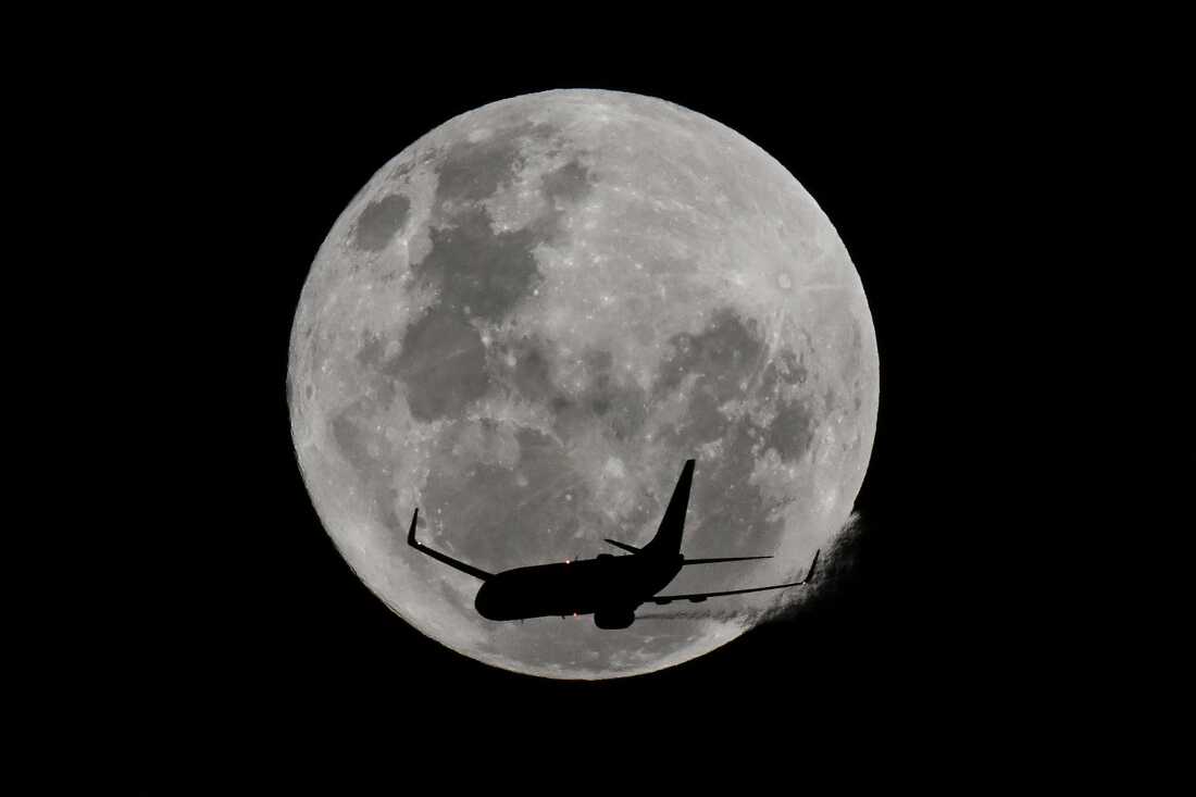 Un avión pasa frente a la luna llena
