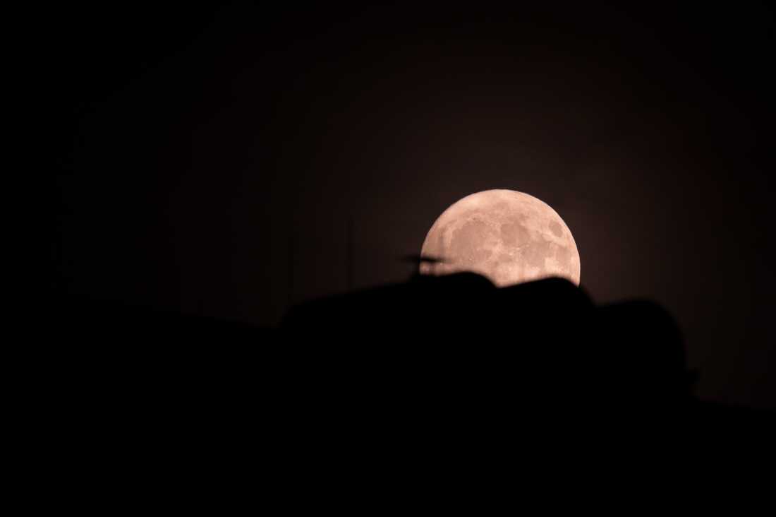 La luna se puede ver detrás de un techo de la casa