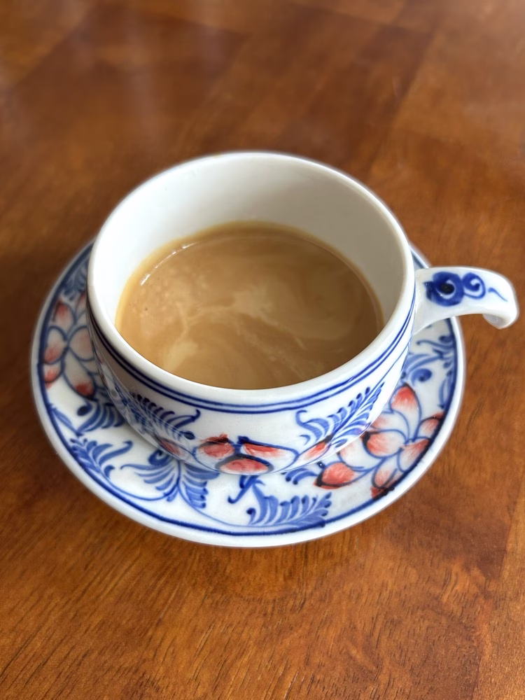 Una toma de espresso elaborada en la máquina de café espresso de Meraki se ve en una taza de café exprés de diseño floral en la parte superior de un platillo a juego.