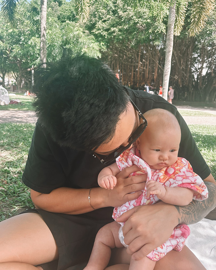 Adulto con un bebé de 5 meses en un parque, destacando la preocupación después del incidente de broma de extintas de incendios por parte de los adolescentes.