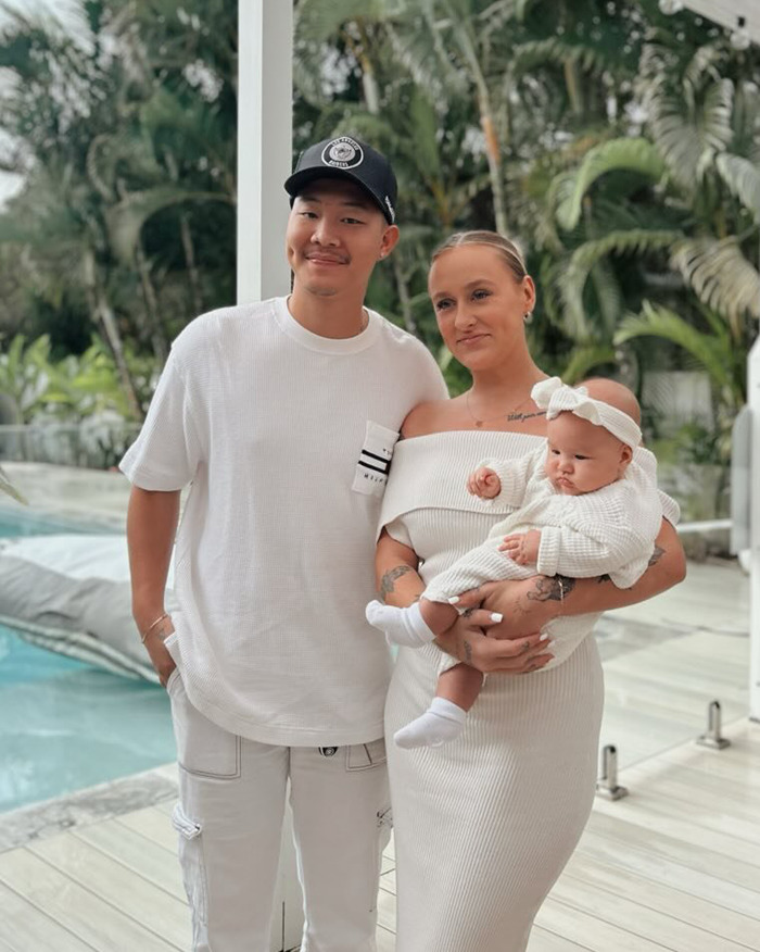 Padres con su bebé de 5 meses vestido de blanco cerca de una piscina al aire libre, reflejando a un bebé de 5 meses corrido al escenario del hospital.